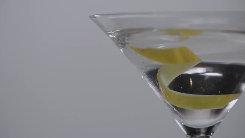 A lemon peel is added to a martini glass