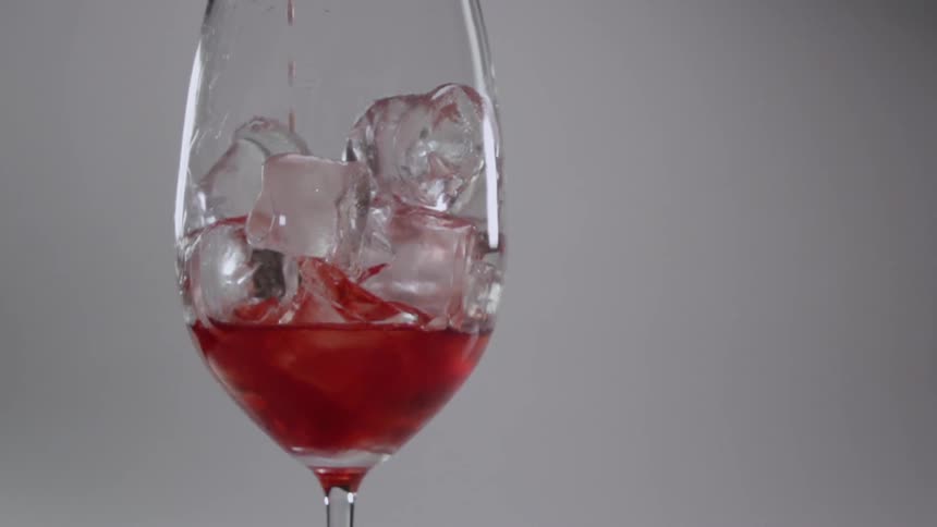 A drink is poured into a wine glass