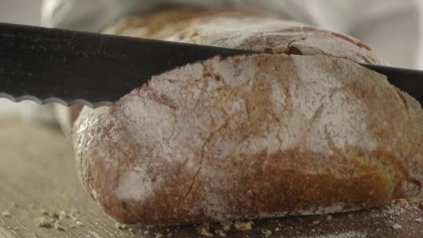 Knife slices a loaf of bread
