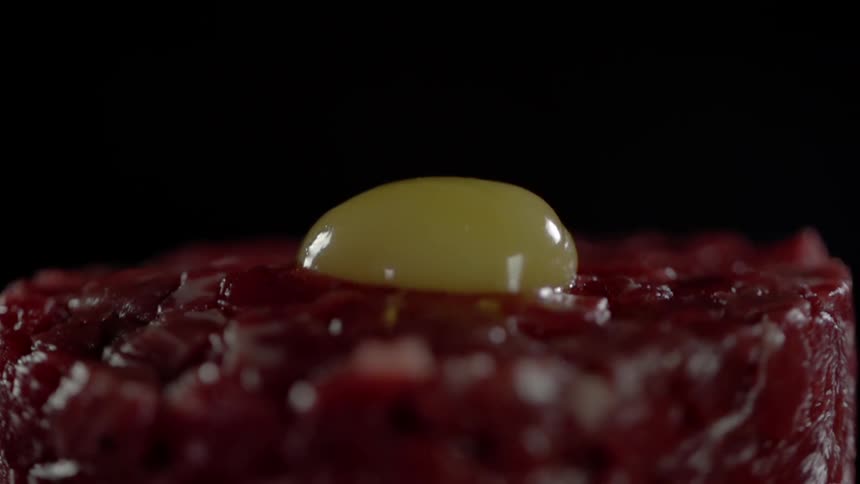 A raw egg falls in the chop meat