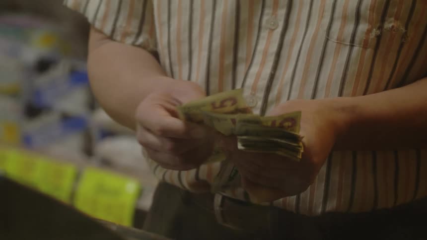 A cashier counts cash in front of a register