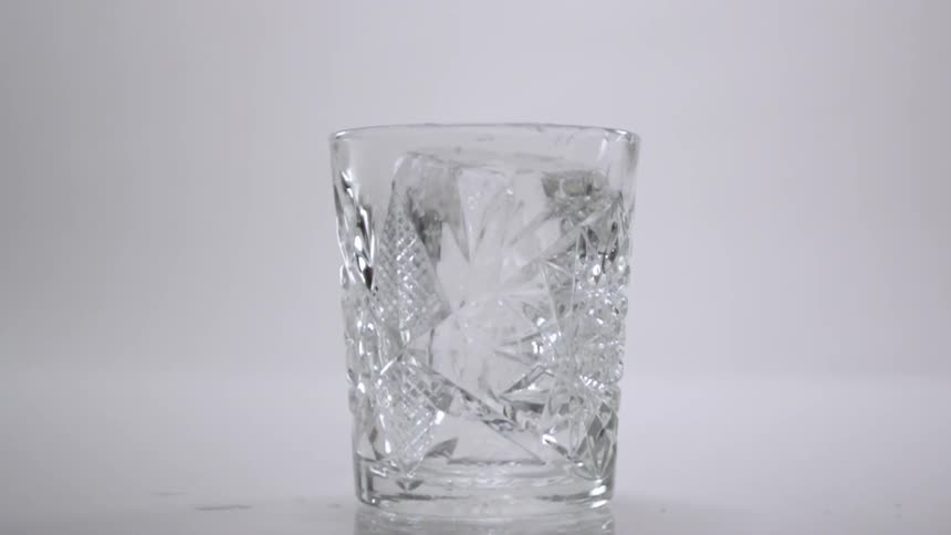 A large ice cube falls into the glass