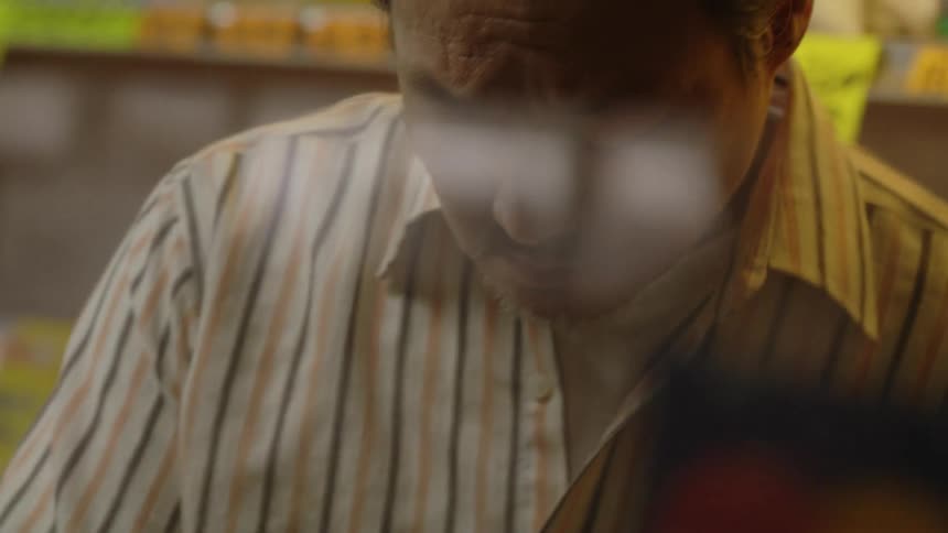 Man  standing behind a counter in a store looking down