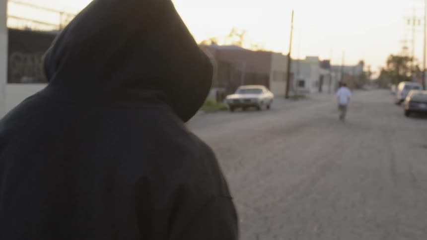 A man with a hoodie walks down the street