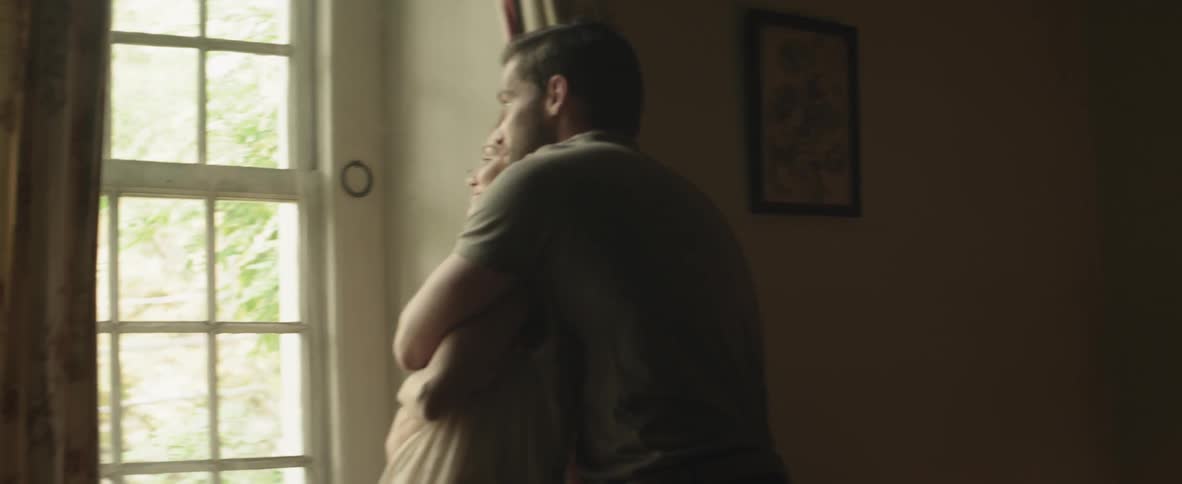 A man embracing a woman from behind as they both look out the window