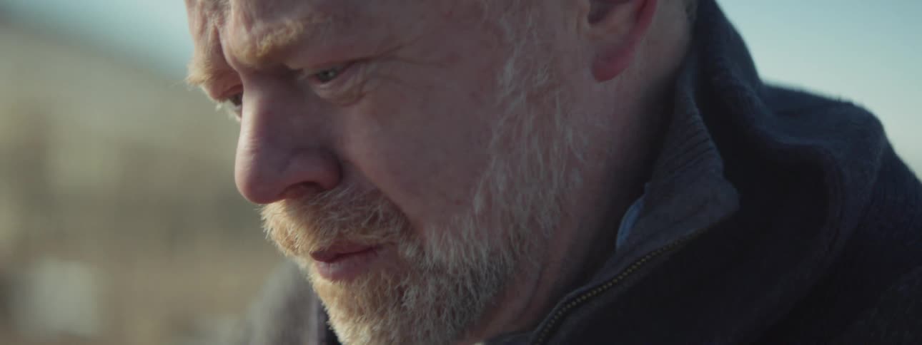 A man is looking down at a card crying
