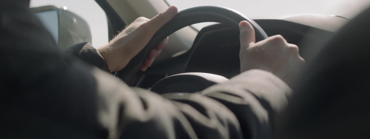 Man grips a steering wheel while driving
