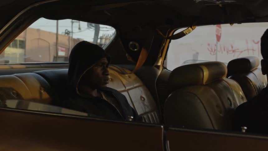 Three men sit in a parked car