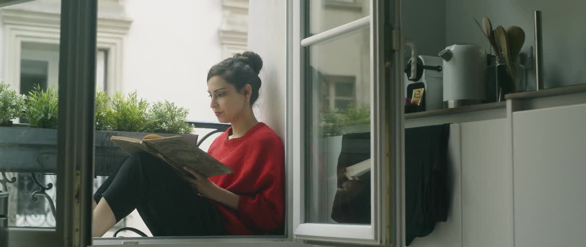 Woman sits on a balcony reading a book