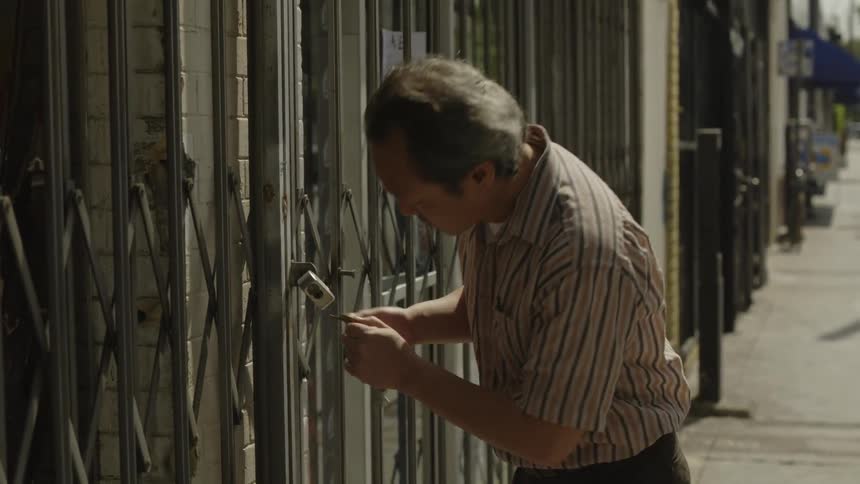 Man unlocks a gate covering a building