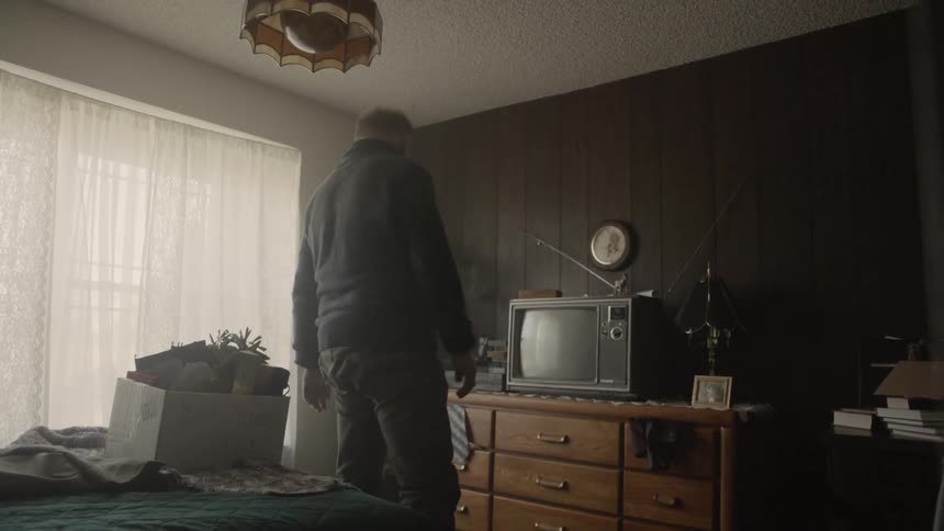 An elderly man stands up from a bed