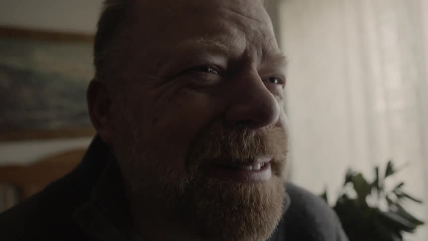 Man cries and smiles while sitting on a bed