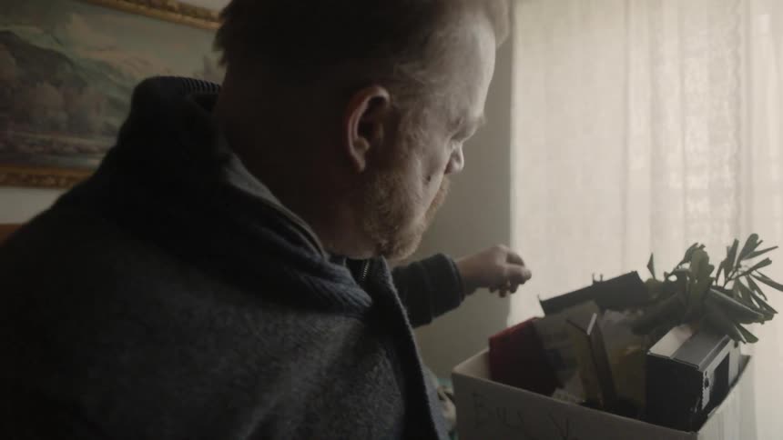 A man searches through items in a box