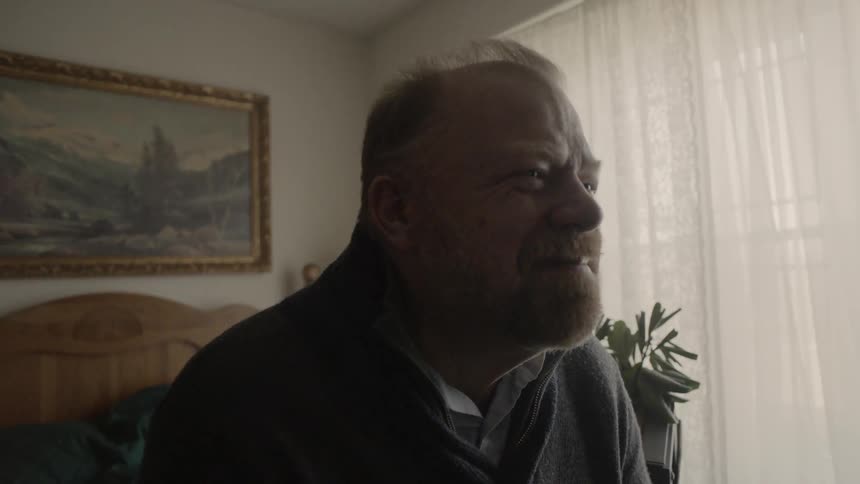 Man smiles while sitting on a bed