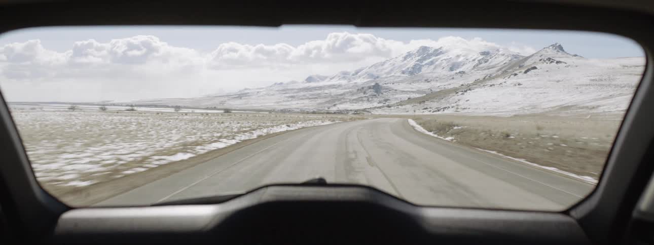 Vehicle travels down a highway next to a snow covered field