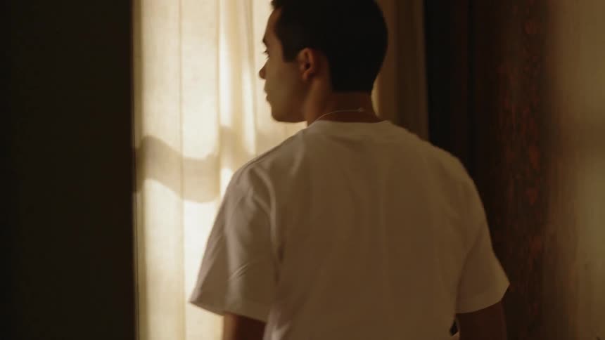 A boy gets up from bed to look towards the window