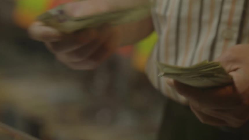 A cashier counts cash by a register