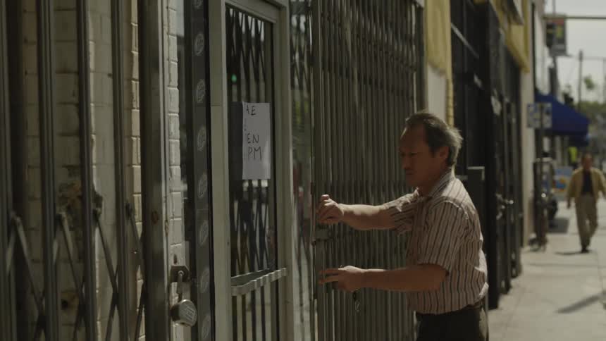 Man opens metal gates protecting a city storefront