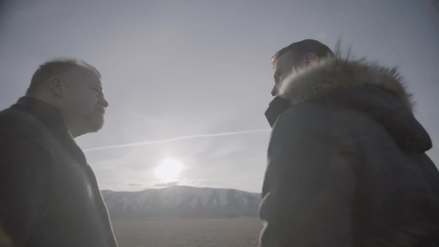 Two men talk face to face at sunset