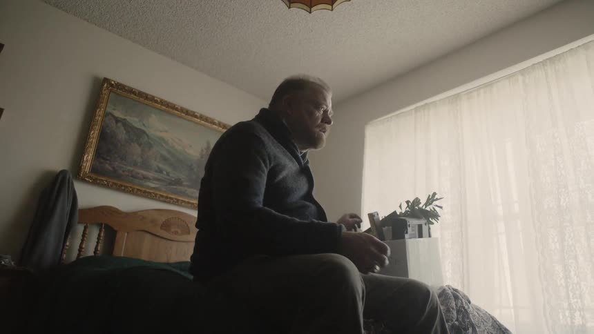 Man stands up from sitting on a bed