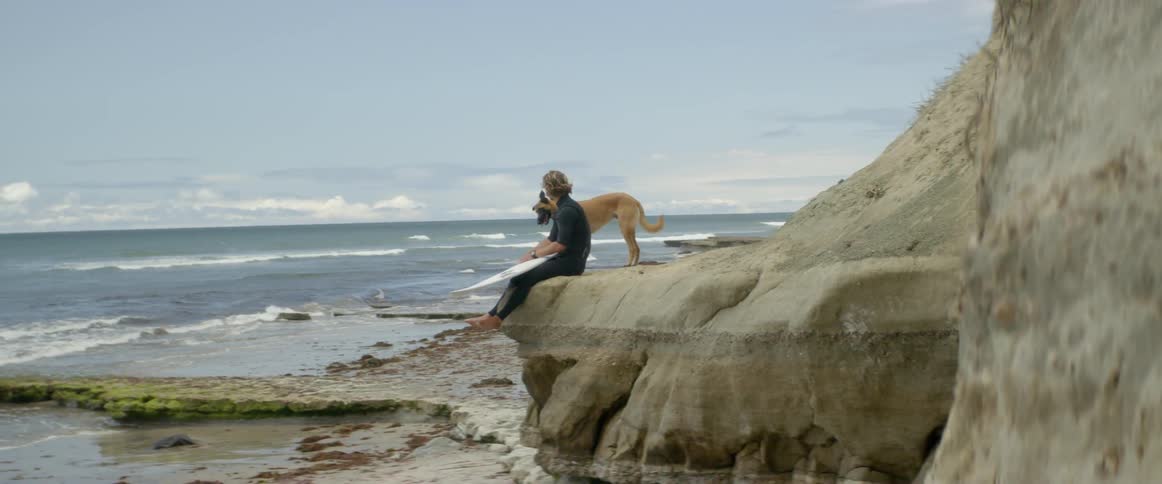 Man and surfer sit on a beach