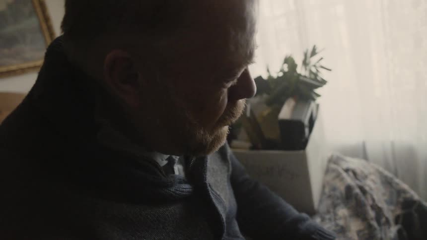 Man cries while looking at framed photographs