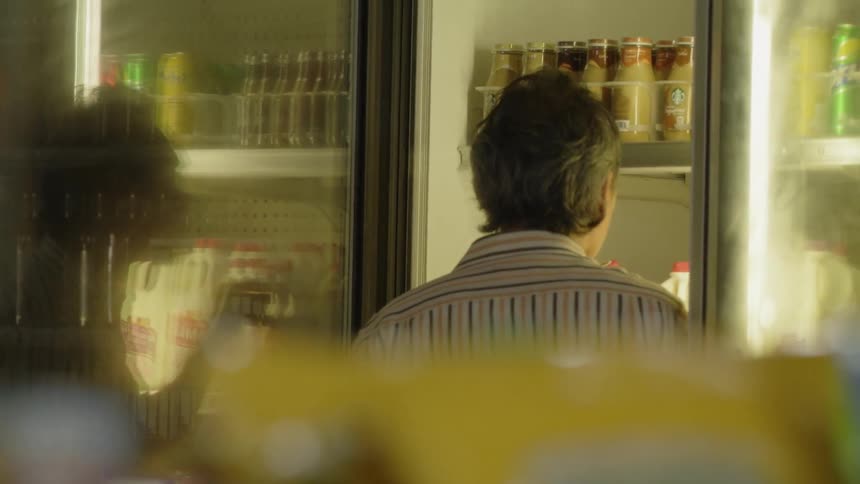 A man is checking items in the store fridge