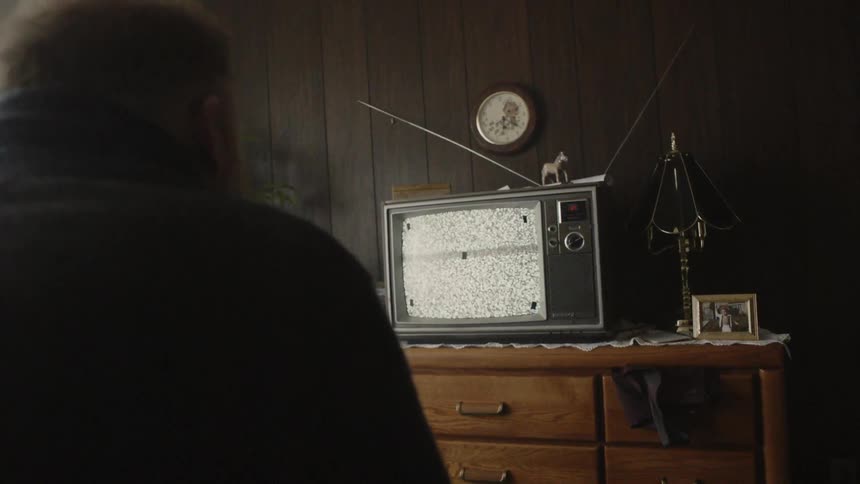 Man looks at a television that has static on the screen