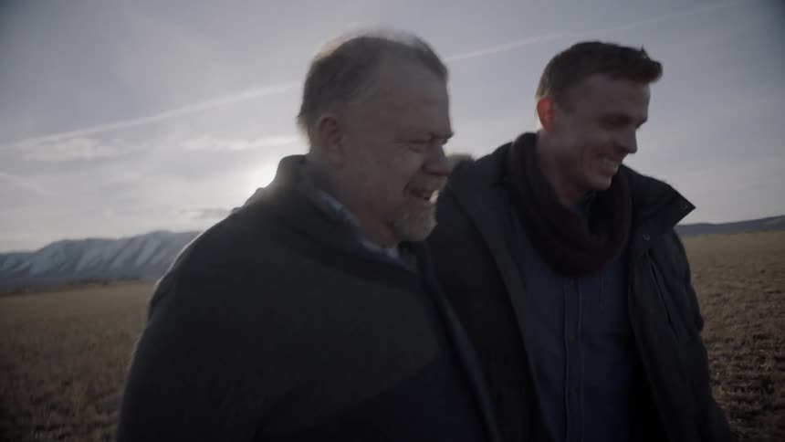 Two men walk together in a large field