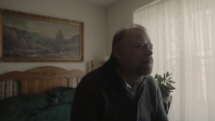 Sad man sits on a bed
