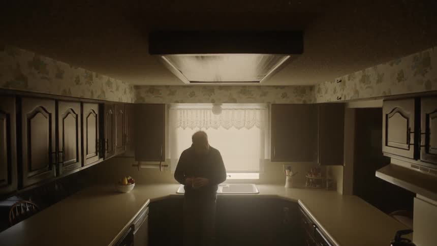 A man leans against his sink with a mug