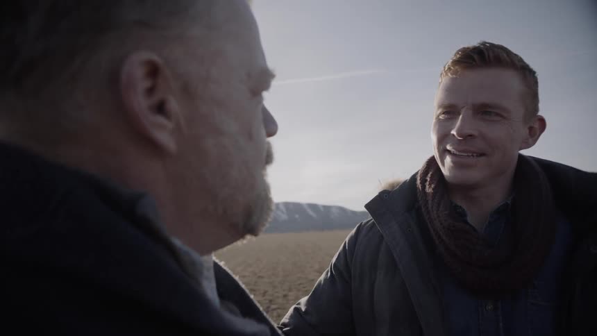 Two men talk in a rural field