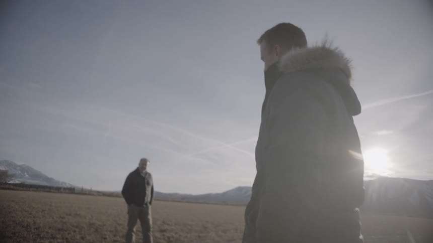 Two men stand in a rural field