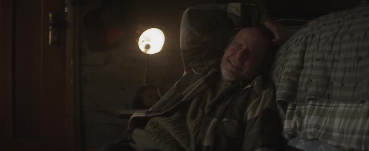 Man crying as he lays back with his hand on his head