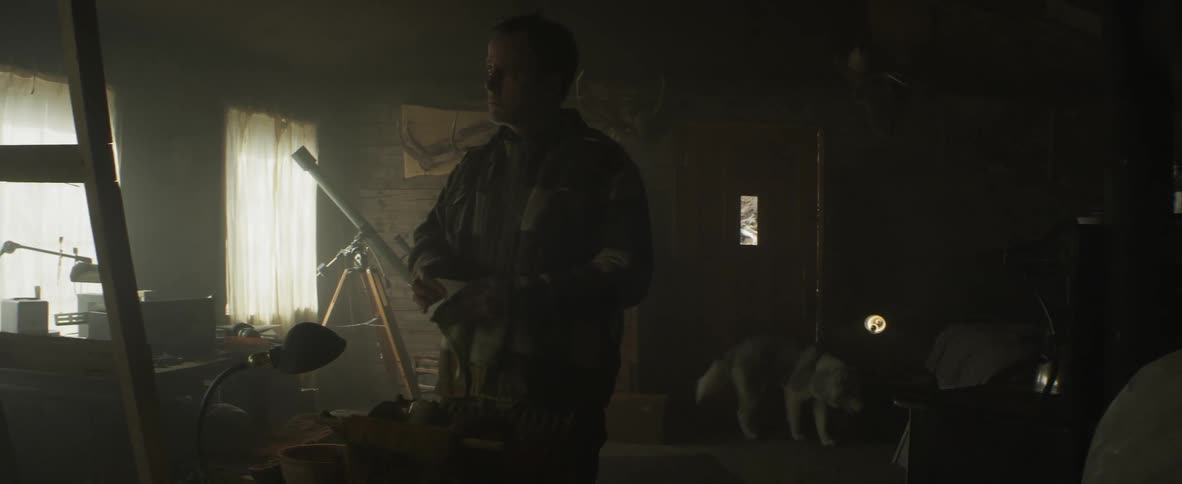 Man stands in a dark room with a telescope