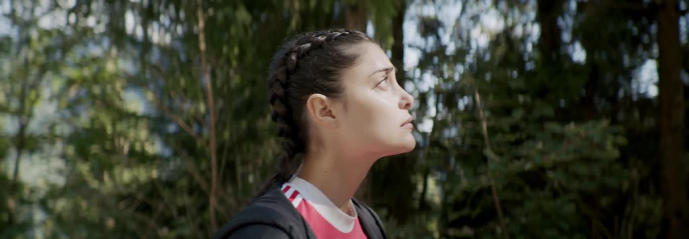 A woman walks through the forest on a sunny day