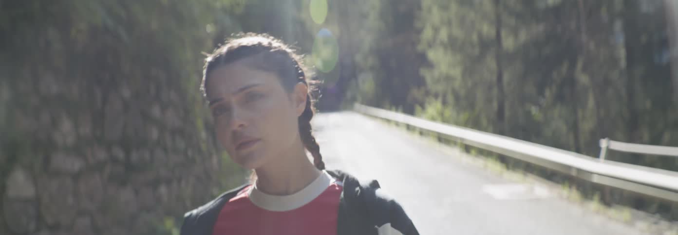The woman is walking down the road on a sunny day