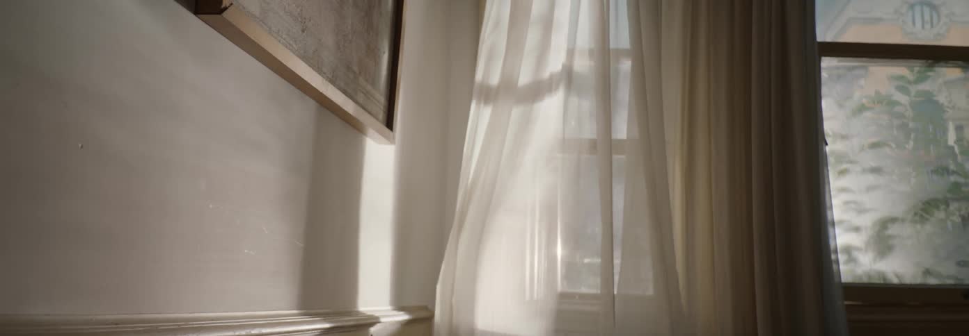 Curtains blow in the breeze at the open window