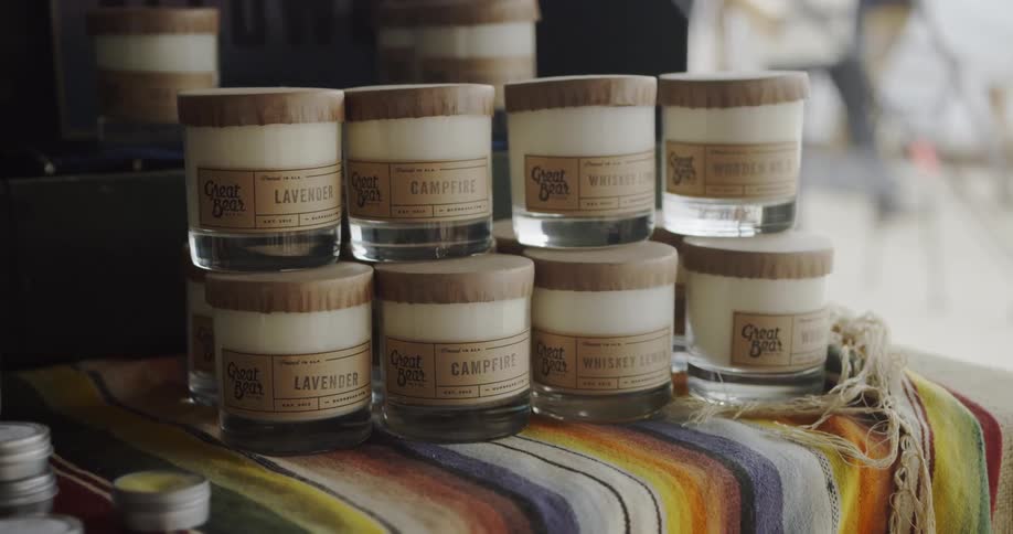 Candles in jars sit in a row on a table