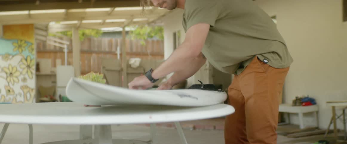 A man is polishing his surfboard