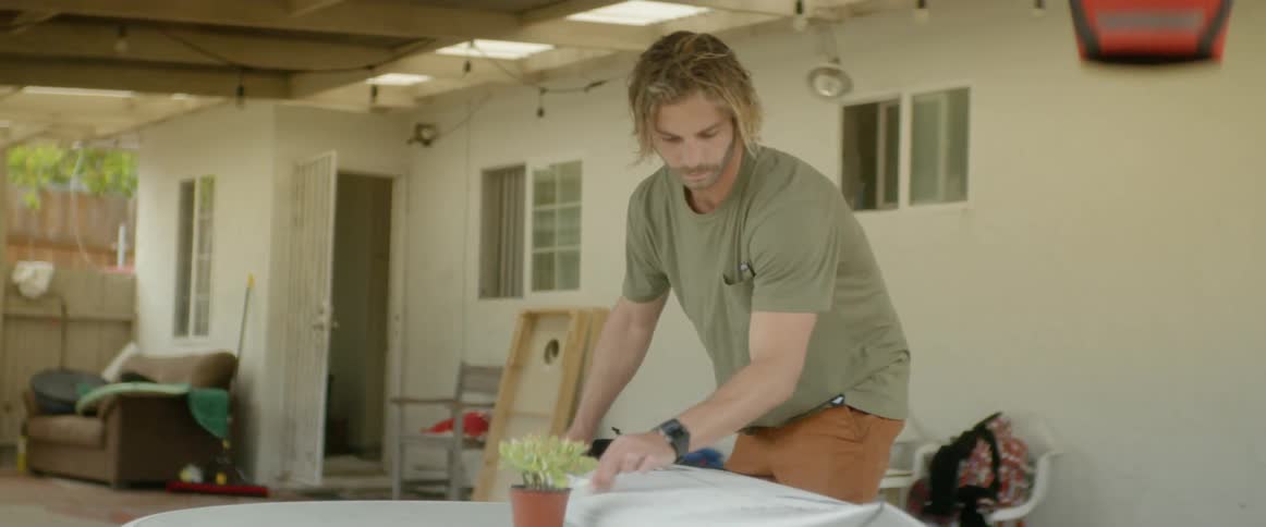 Man rubs wax on a surfboard