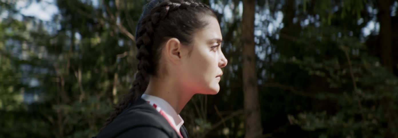 A woman slowly walks forward in the woods