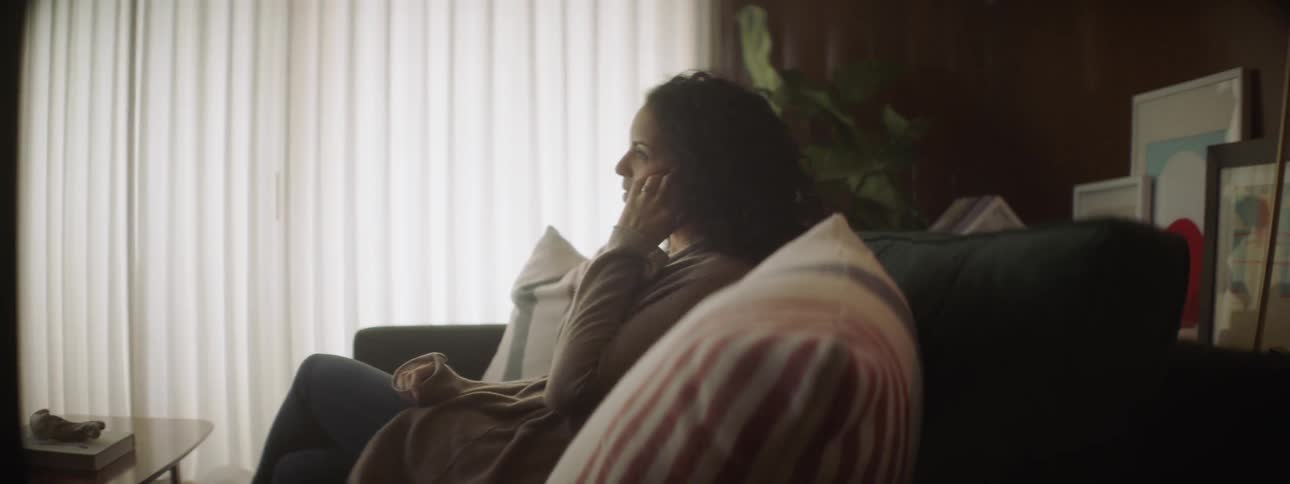Woman talks on the phone while sitting on a couch