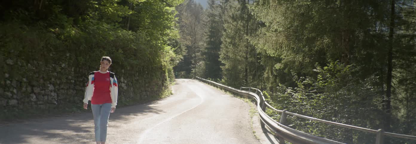 A woman walks on a mountain road