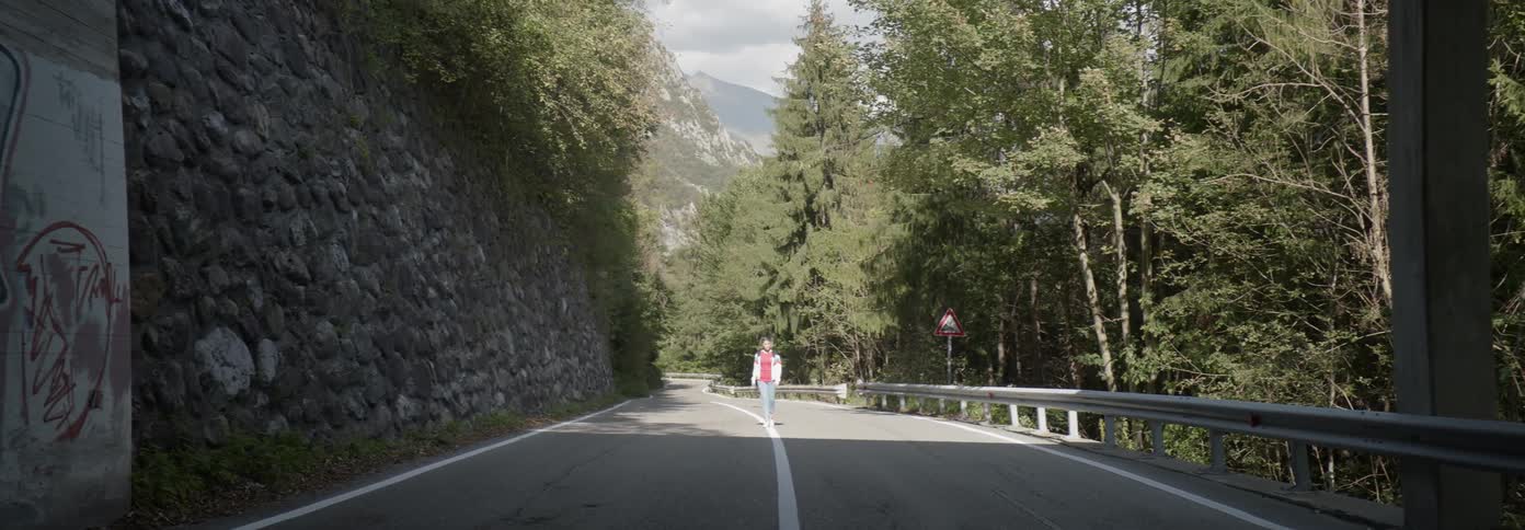 A woman is walking down the road towards a tunnel