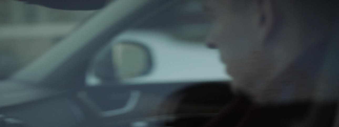 A man sits in a car in a driveway