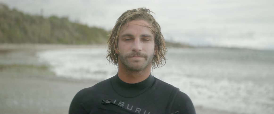 A man standing in the surf smiles