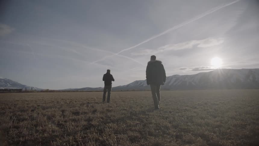 Two men walk together in a field