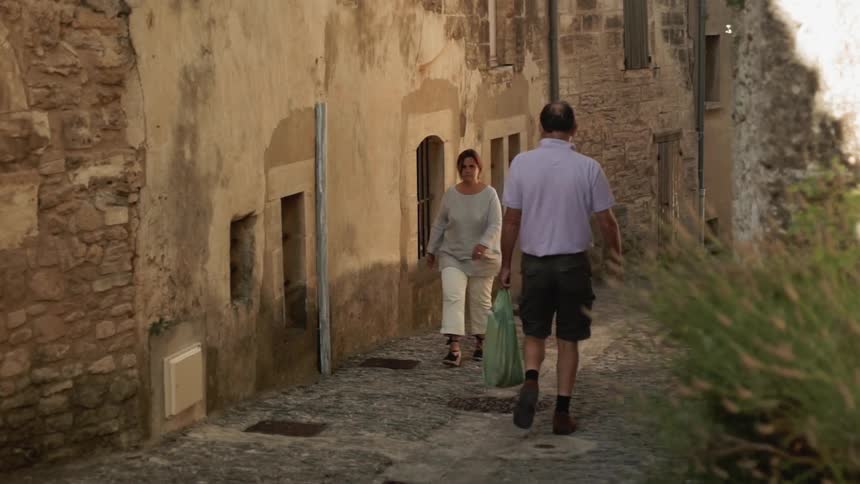 A man and woman walking on a stone path pass each other