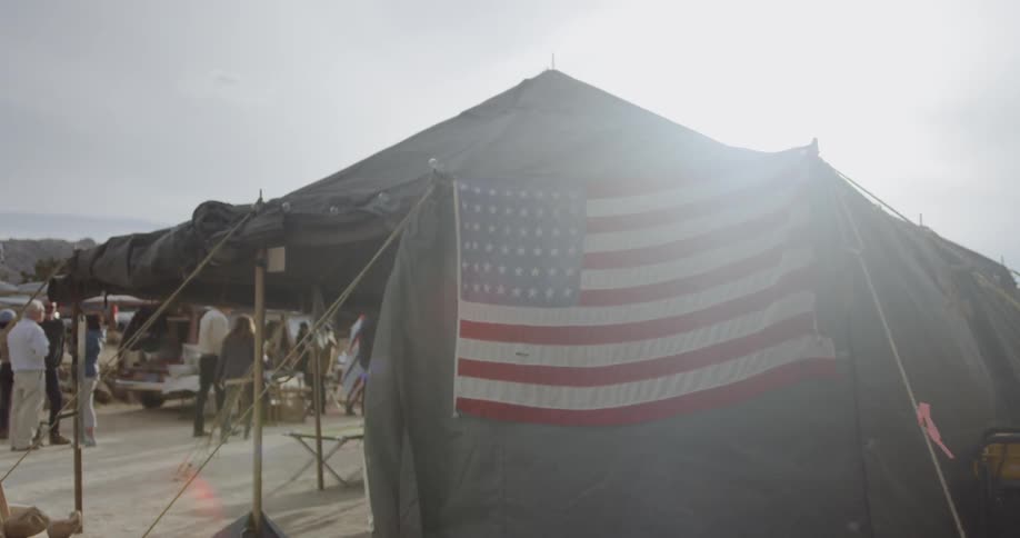 American flag hangs from a pole near a tent